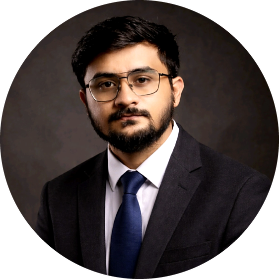 Photo of Abhipriyo Banerjee in a dark suit and blue tie